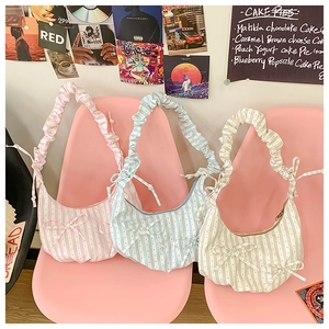 Three striped polka dot dumpling bags in pink, blue and beige on a pink chair