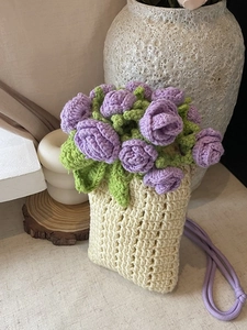 Handmade knitted bucket phone bag with purple floral crochet patterns and a purple strap