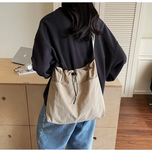 Back view of model wearing a large beige nylon bucket bag in a modern home setting