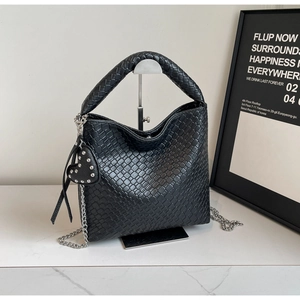 Detail of black woven leather bucket bag with silver heart charm and metal chain strap