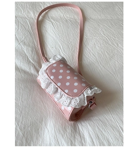 Close-up of pink polka dot bag with white lace trim on soft white fabric background