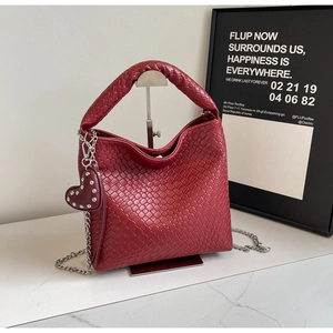 Close-up of deep red woven bucket bag with intricate leather texture and heart charm