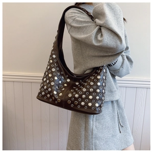Brown leather hobo bag with silver studs worn by model in casual grey suit outfit