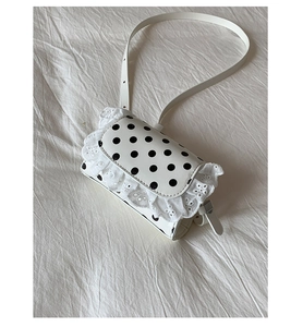 Close-up of white polka dot crossbody bag with delicate lace trim and leather strap