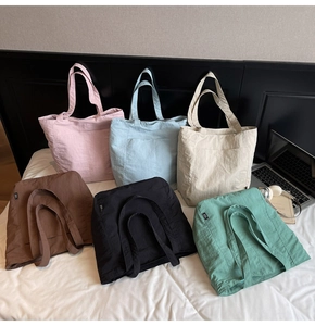 Showcase of six various minimalist tote bags in nylon fabric on a white bed sheet