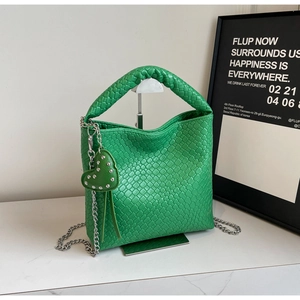 Detail of green woven bucket bag with silver chain strap and heart charm decoration