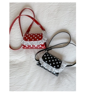 Detailed view of red and black polka dot mini crossbody bags with white lace trim and straps
