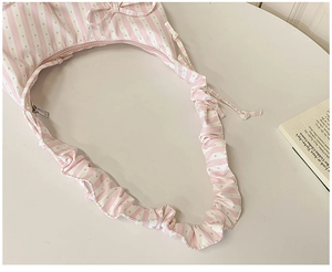 Detail of pink and white striped dumpling bag with ruffled straps and bow accent