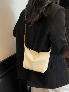 Chic cream nylon dumpling bag with a unique woven brown strap shown on a shoulder