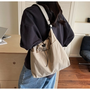 Detail view of khaki nylon bucket bag with adjustable wide strap and side pockets
