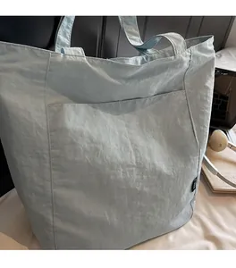 Detail of light blue nylon tote bag with crinkled texture fabric and front pocket