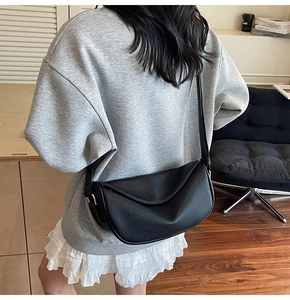 Modella che indossa una borsa a tracolla a mezzaluna nera in pelle con fibbia dorata