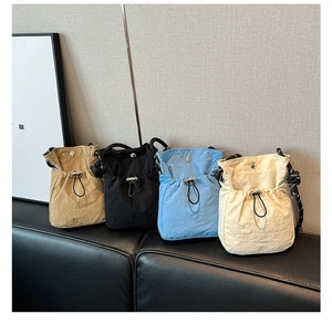 Detailed display of small nylon drawstring bucket bags in khaki, black, blue, and beige