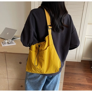 Rear view of a model wearing the bright yellow nylon drawstring bucket bag in a casual style