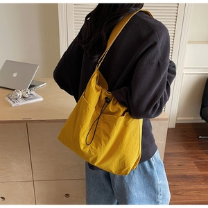 Detail of yellow nylon crossbody bucket bag with drawstring closure and adjustable strap