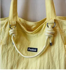 Détail d'un sac cabas en nylon jaune avec poignées en corde et étiquette de mode