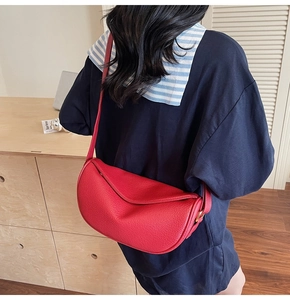 Borsa a mezzaluna in pelle rossa con tracolla regolabile e dettagli dorati su modella