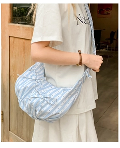 Close-up of sky blue striped fabric texture and delicate bow details on crescent bag