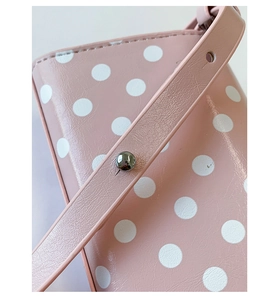 Detail of pink polka dot bag showing silver rivet fastening and adjustable shoulder strap
