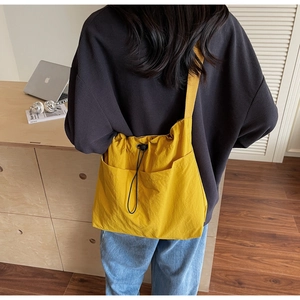 Detail of a bright yellow drawstring bucket bag with adjustable shoulder strap