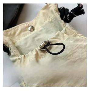 Close-up of drawstring closure on light beige nylon bucket bag with silver metal eyelets