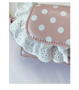 Macro view of pink polka dot handbag with white lace embroidery and fine stitching