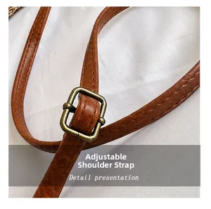 Detailed macro view of brown PU leather shoulder strap with bronze metal buckle and stitching