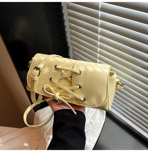 Close-up of pale yellow PU leather crossbody bag with lace-up detail and a sweet bow knot