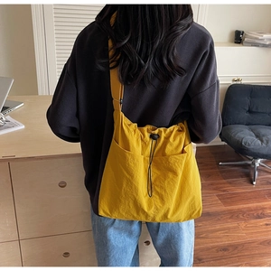 Detail of yellow nylon bucket bag featuring drawstring closure and double front pockets
