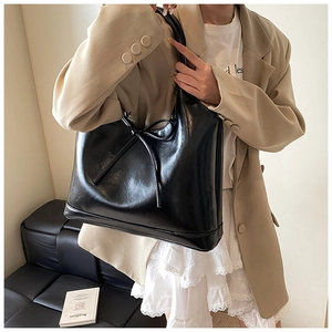 Close-up of black glossy PU leather tote bag with elegant bow detail for women
