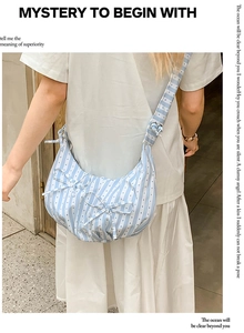 Detail showing blue and white striped crossbody dumpling bag with ribbon bow accents