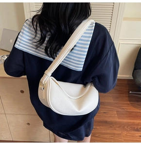 Borsa a mezzaluna bianca con trama litchi indossata da una modella in ufficio moderno
