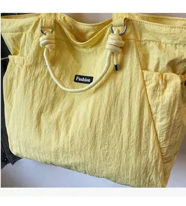 Détail du sac cabas en nylon jaune avec texture froissée et anses en corde blanche