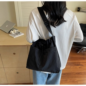 Detailed view of a black large capacity nylon crossbody bag worn by a model for daily use