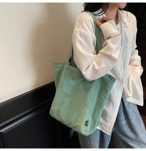 Detail of green nylon tote bag featuring a spacious side pocket and lightweight texture