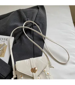 Détail du mini sac bandoulière en cuir blanc avec fermoir cœur doré et broderie marguerite