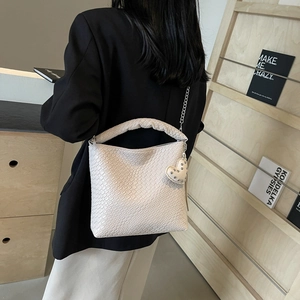 Minimalist beige woven bucket bag with heart charm and silver chain strap for women