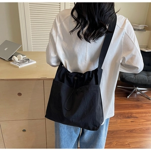 Detail of black large capacity shoulder bag with drawstring closure on model