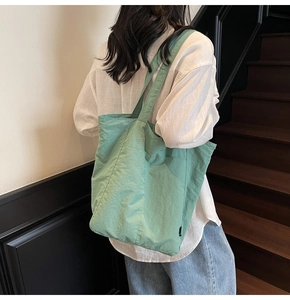 Close-up of a light green large-capacity tote bag made of textured nylon fabric
