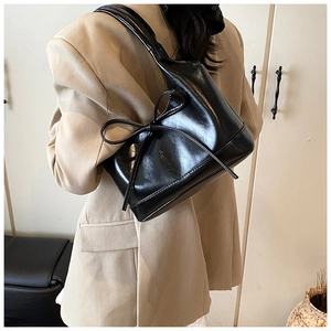 Chic black PU leather tote bag with large decorative bow shown in a real-life carrying style