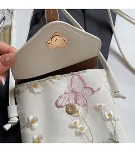 Gros plan sur le sac de téléphone brodé blanc avec un fermoir magnétique en forme de cœur