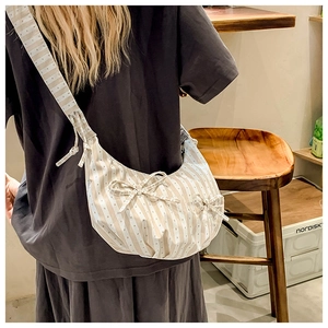 Detail view of striped canvas hobo bag with bows on shoulder strap for women