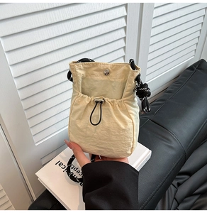 Detail of yellow nylon drawstring crossbody bag with textured strap and magnetic closure