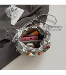 Top view of spacious silver pleated bucket bag interior showing brown lining and beads