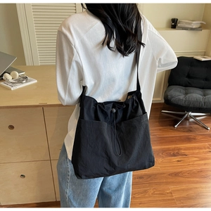 Detail of black nylon drawstring bucket bag with large front pockets on a model