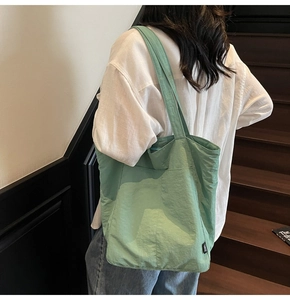 Detailed view of lightweight mint green nylon tote bag featuring front pocket and woven label