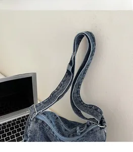 Detail of adjustable shoulder strap and zipper closure on a washed denim tote bag