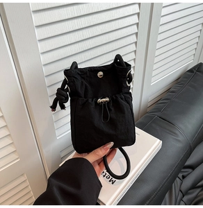 Detail view of black drawstring bucket bag with adjustable cords and tactical nylon fabric