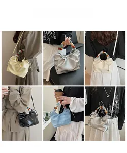 Detailed views of pleated bucket bags with colorful acrylic beaded handles in five colors
