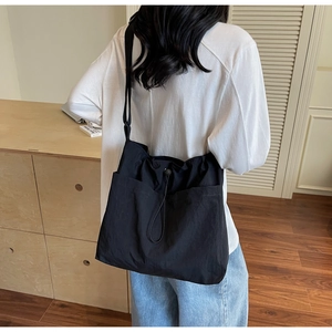Detail of black large capacity nylon tote bag with drawstring closure on model
